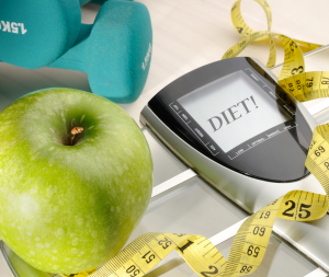 Een foto van een appel, meetlint een apparaat die BMI meet en gewichtjes